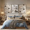 A cozy bedroom with a blue and beige color scheme. Above the bed, three framed Zen Garden Prints featuring stones and sand patterns enhance the serene, Japandi-inspired decor. Soft lighting adds warmth and tranquility.
