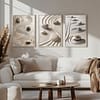 A modern living room in warm brown and beige tones. Above the sofa, three Zen Garden Prints in matching frames enhance the Japandi aesthetic. The minimalist decor and neutral palette create a serene and elegant ambiance.