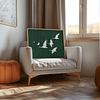 A framed Japandi Wall Art piece with white birds on a deep green background is propped on a cream armchair in a sunlit room. An orange pouf and a window nearby add to the cozy ambiance.