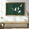 A Framed Japandi Wall Art of white cranes flying against a dark green background hangs on a white wall above a rustic wooden bench. The bright, serene setting embodies minimalist decor.