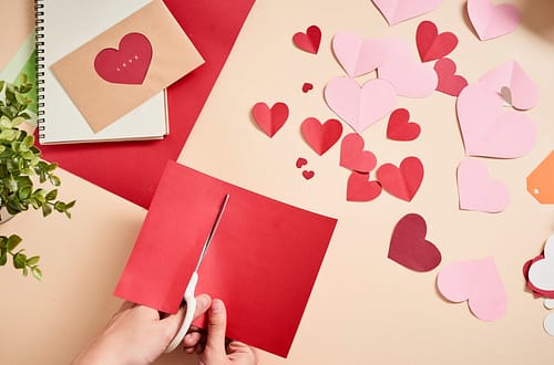 woman-cuts-out-red-felt-hearts-homemade-crafts