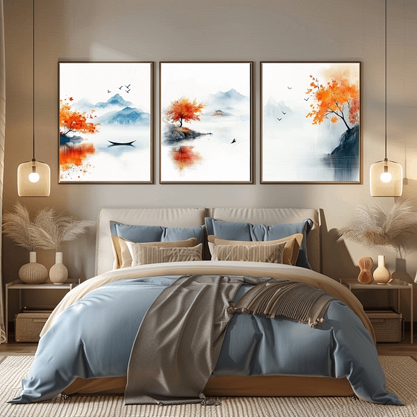 Three framed Japandi autumn decor prints are above a beige bed. The room features blue and beige bedding, warm lighting, and soft, earthy decor. The prints' autumn colors of orange and blue create a cozy atmosphere.