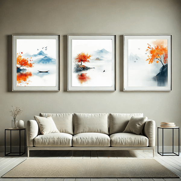 A minimalist living room featuring three framed Japandi autumn decor prints in muted orange and blue tones. The frames hang above a beige sofa, with small black side tables adding a modern touch. The room is light and calming, with soft colors and simple decor.