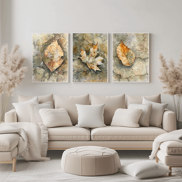 A modern living room with three wabi-sabi leaf art pieces above a soft beige couch. The autumn-colored leaves in shades of brown, orange, and green add a serene, natural vibe. The neutral decor, with pampas, grass, and pillows, enhances the calming atmosphere.