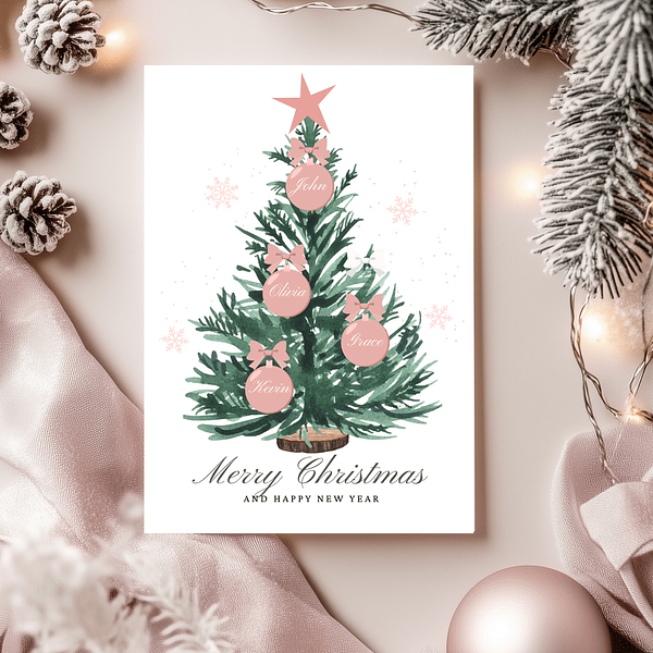 Personalized Christmas card with a green tree and rose gold ornaments showing family names. The card is paired with pink Christmas decorations, creating a soft, festive vibe.